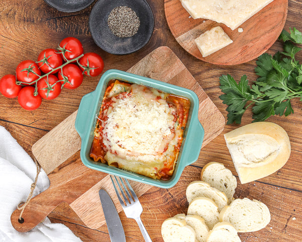 Baked Lasagna with bread, parsley, parmesan, pepper and tomatoes around it