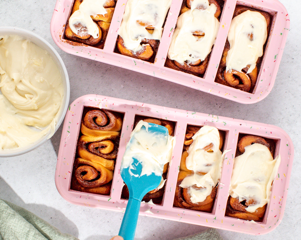 Mini Cinnamon Rolls with Cream Cheese Frosting (Freezer-Friendly!) in Souper Cubes 1-cup silicone trays spreading cream cheese frosting.