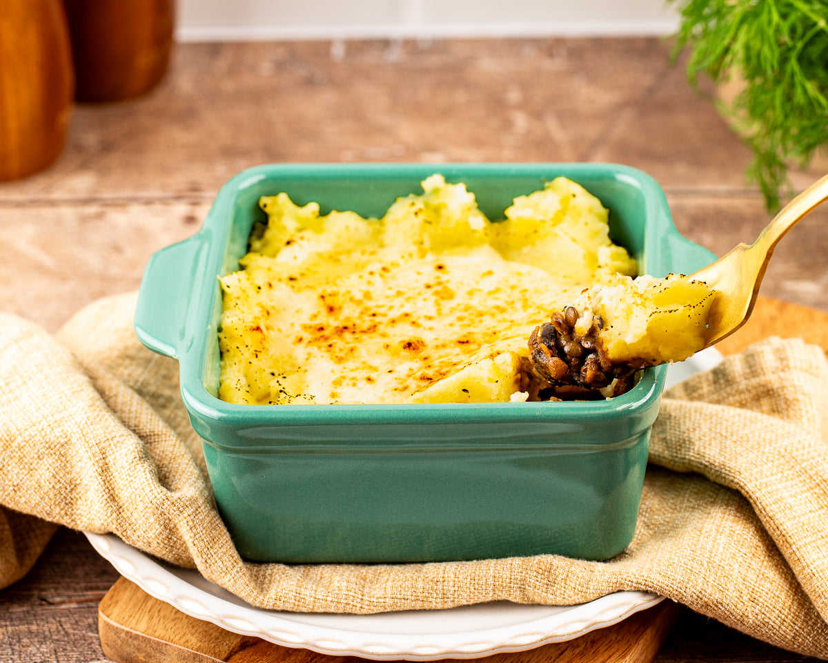 vegetarian shepherd’s pie with golden broiled mashed potato topping in a kale stoneware baking dish