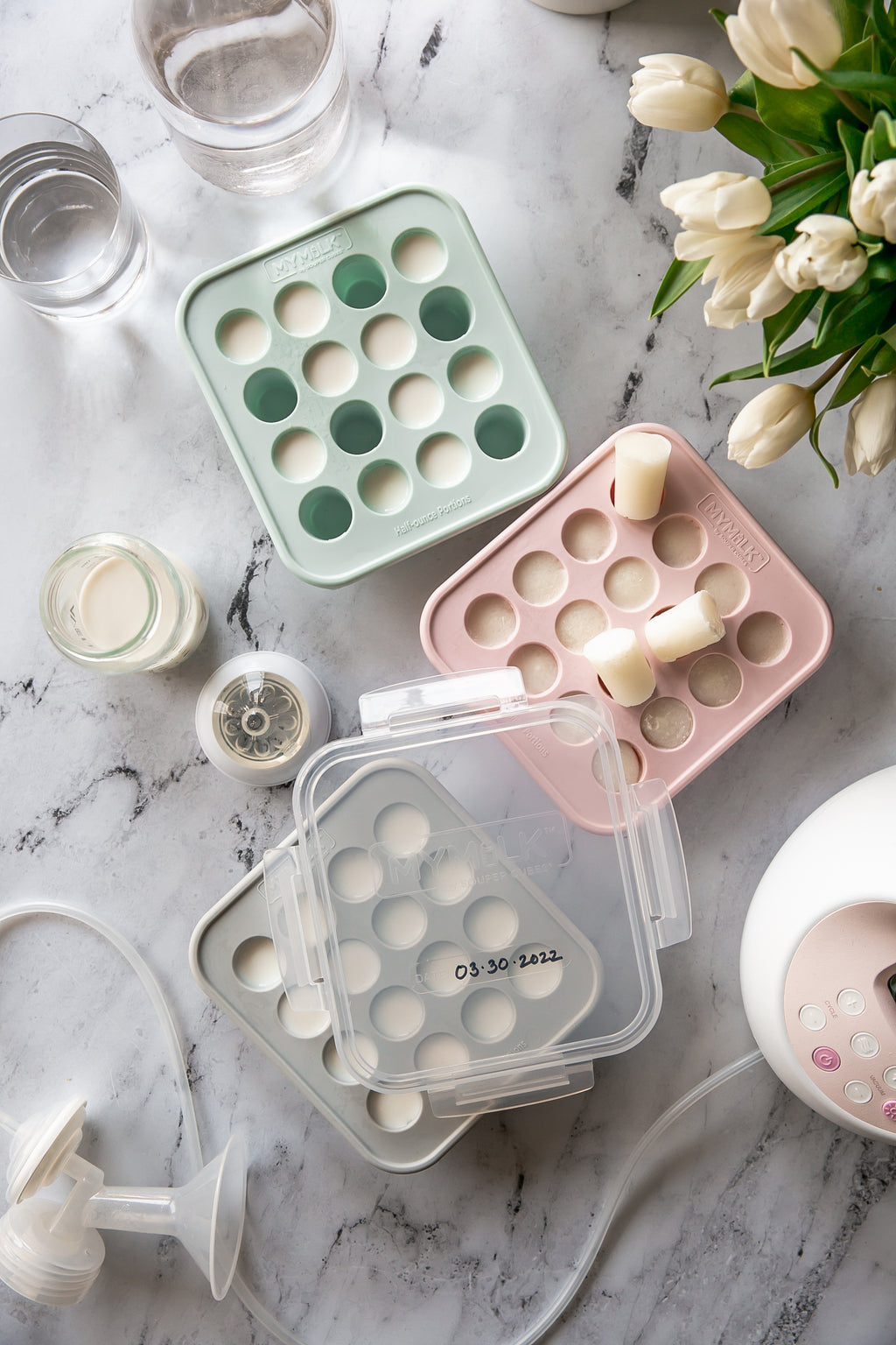 A flat lay with MyMilk trays filled with frozen breast milk and tulips 