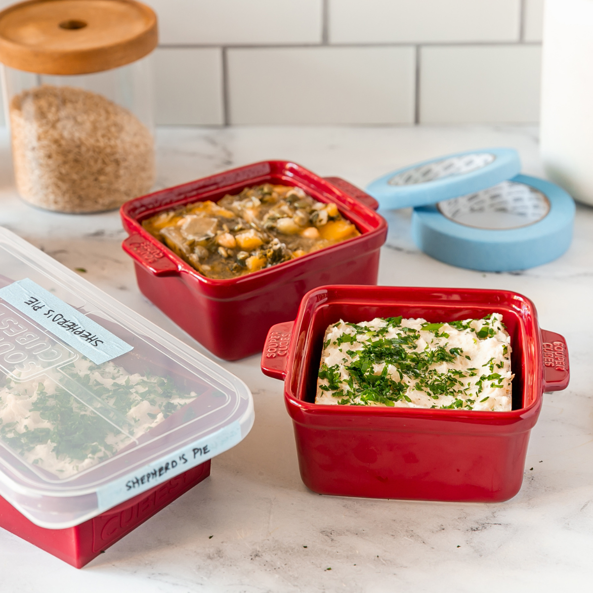 Red food storage containers with labeled lids on a kitchen counter.