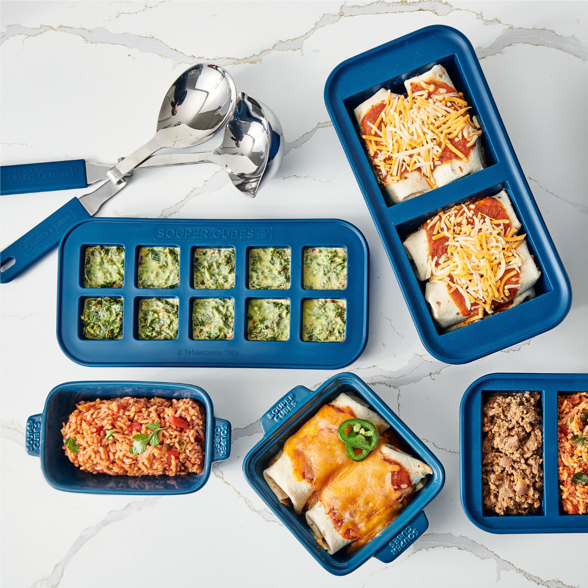 Blue silicone Souper Cubes with various food items on a marble surface