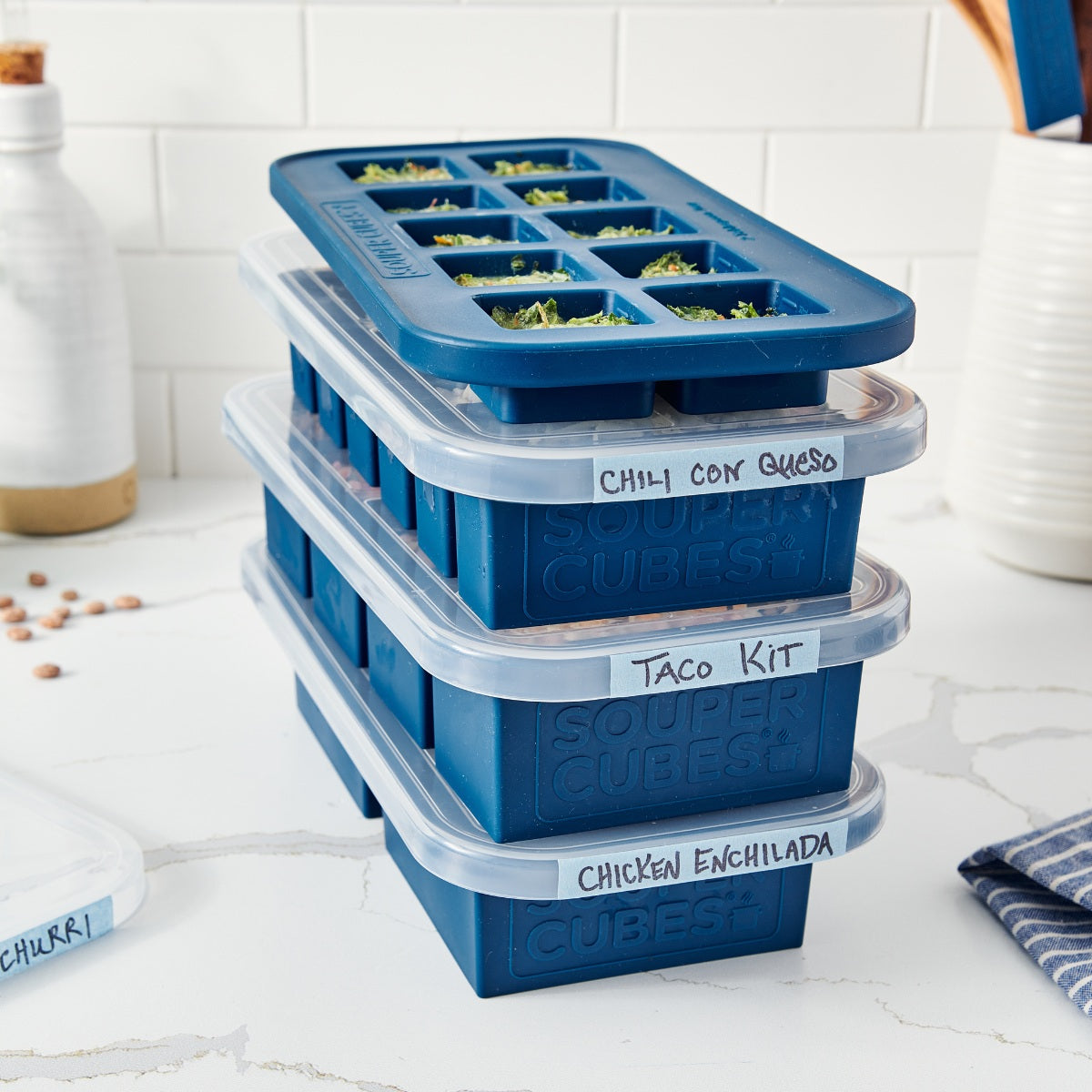Stack of blueberry freezer trays with labeled sections on a kitchen counter.