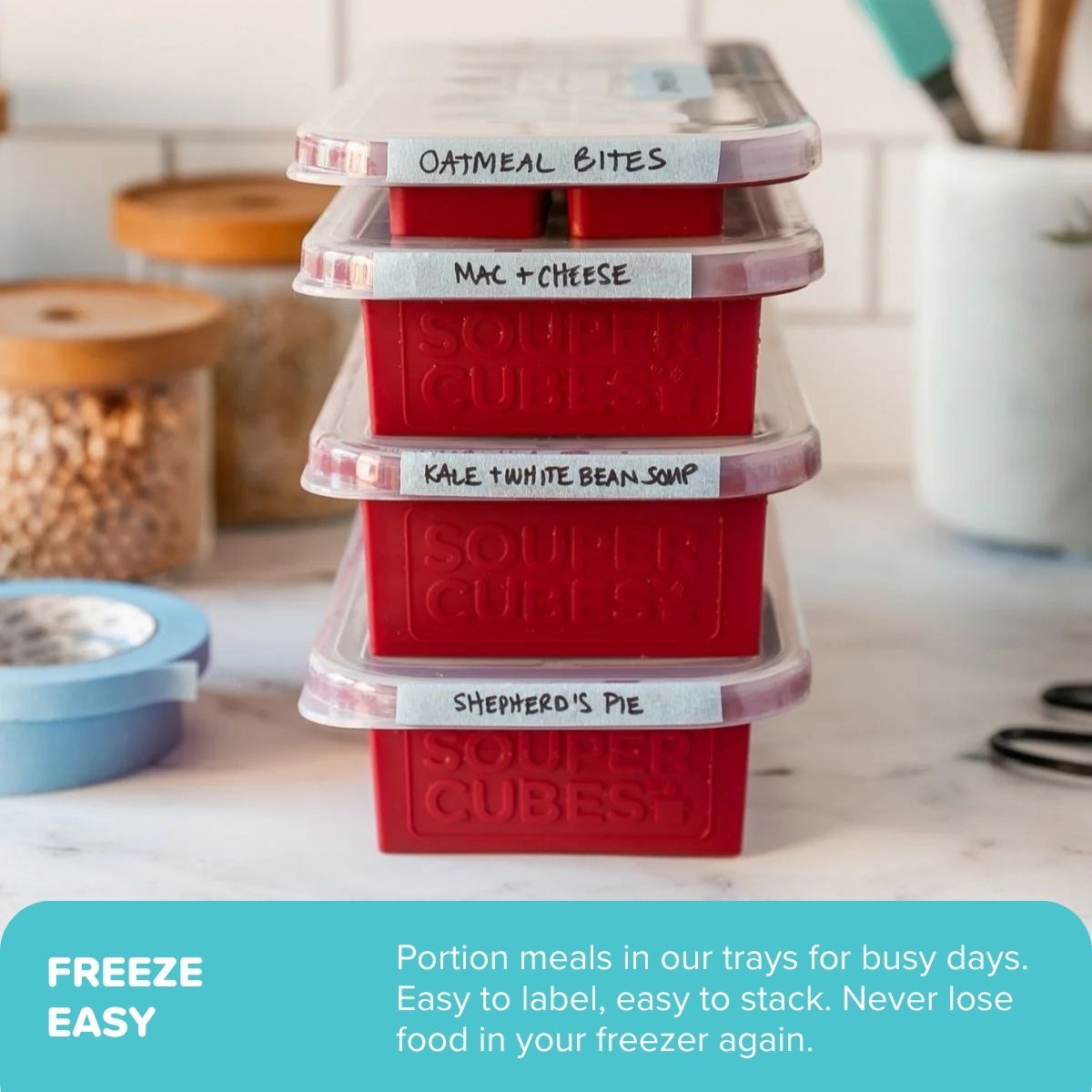 Stack of cranberry Souper Cubes trays with labels on a kitchen counter.