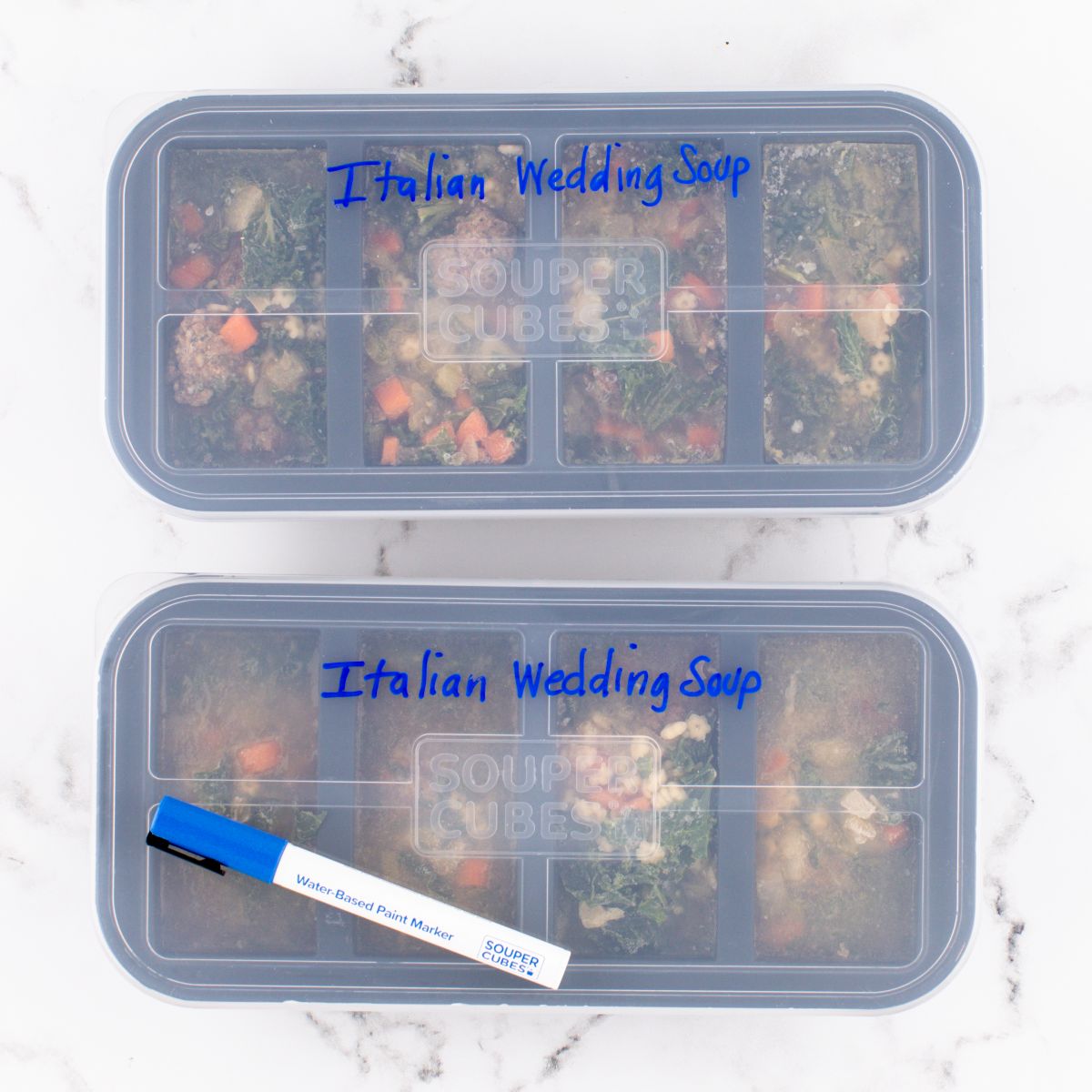 Two containers of 'Italian Wedding Soup' with a water-based paint kitchen marker on a marble surface.