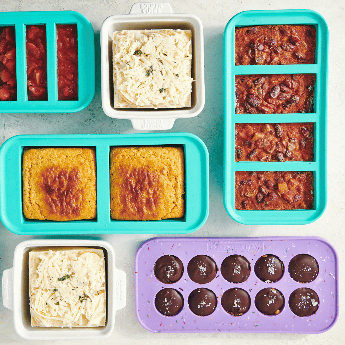 Silicone molds filled with various food items on a gray surface