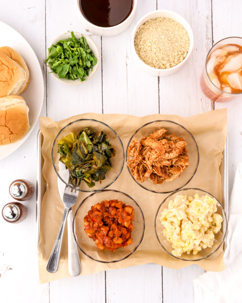 Photo of BBQ chicken, collard greens, baked beans and mac & cheese on a tray