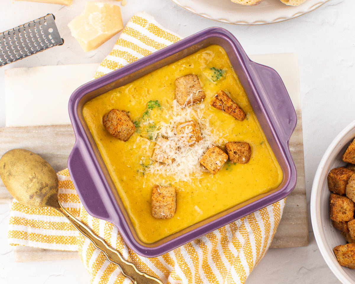 broccoli cheddar soup in a ceramic baking dish with fresh broccoli