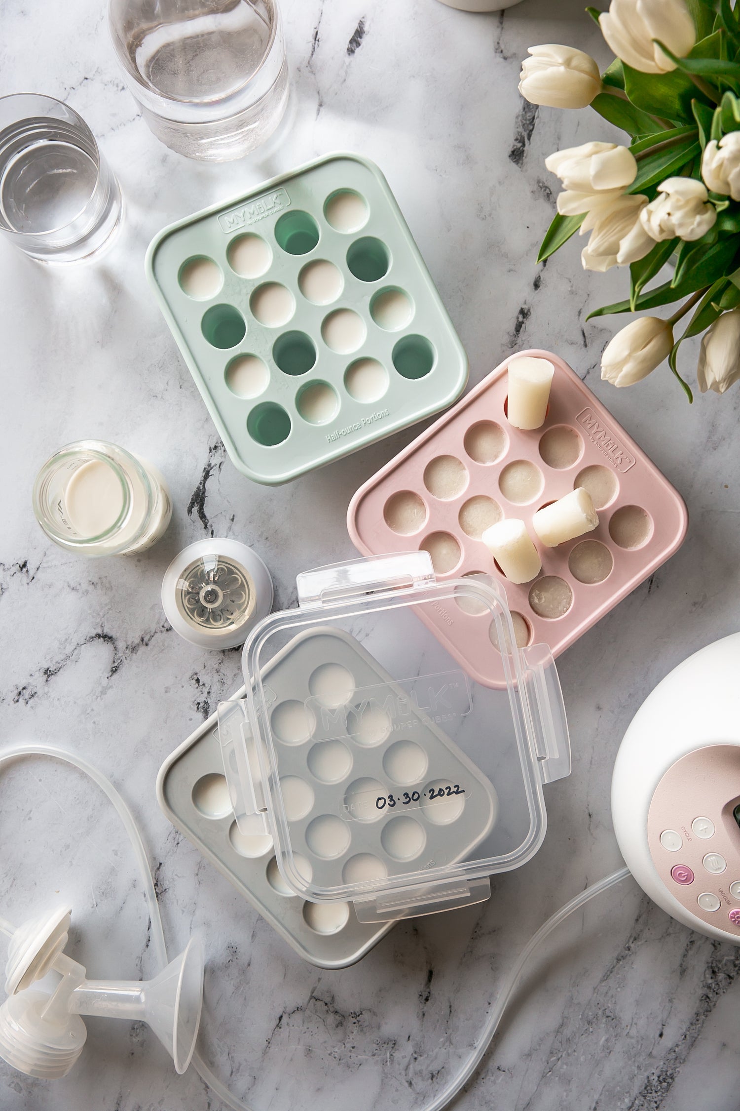 A flat lay with MyMilk trays filled with frozen breast milk and tulips 