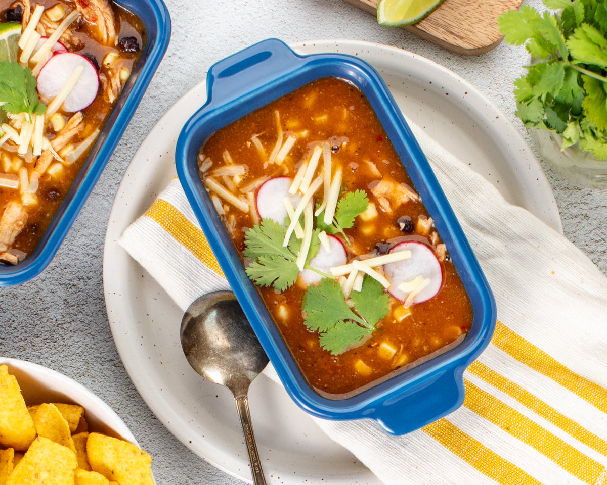 (soup in bowl with garnishes next to Ceramic Baking Dishes): easy chicken tortilla soup in bowl with avocado, cilantro, and tortilla chips next to Souper Cubes Ceramic Baking Dishes