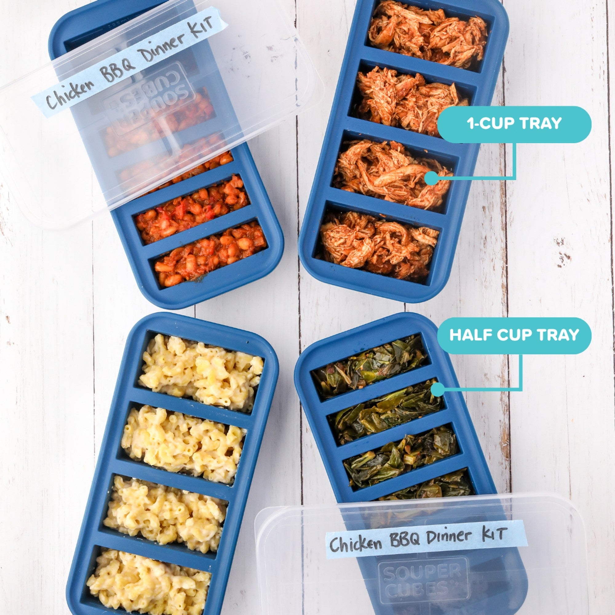 Four blue silicone dinnerware trays arranged on a white wood surface, filled with different foods. Two clear lids are placed on top, one labeled 'Chicken BBQ Dinner Kit' and another partially visible.