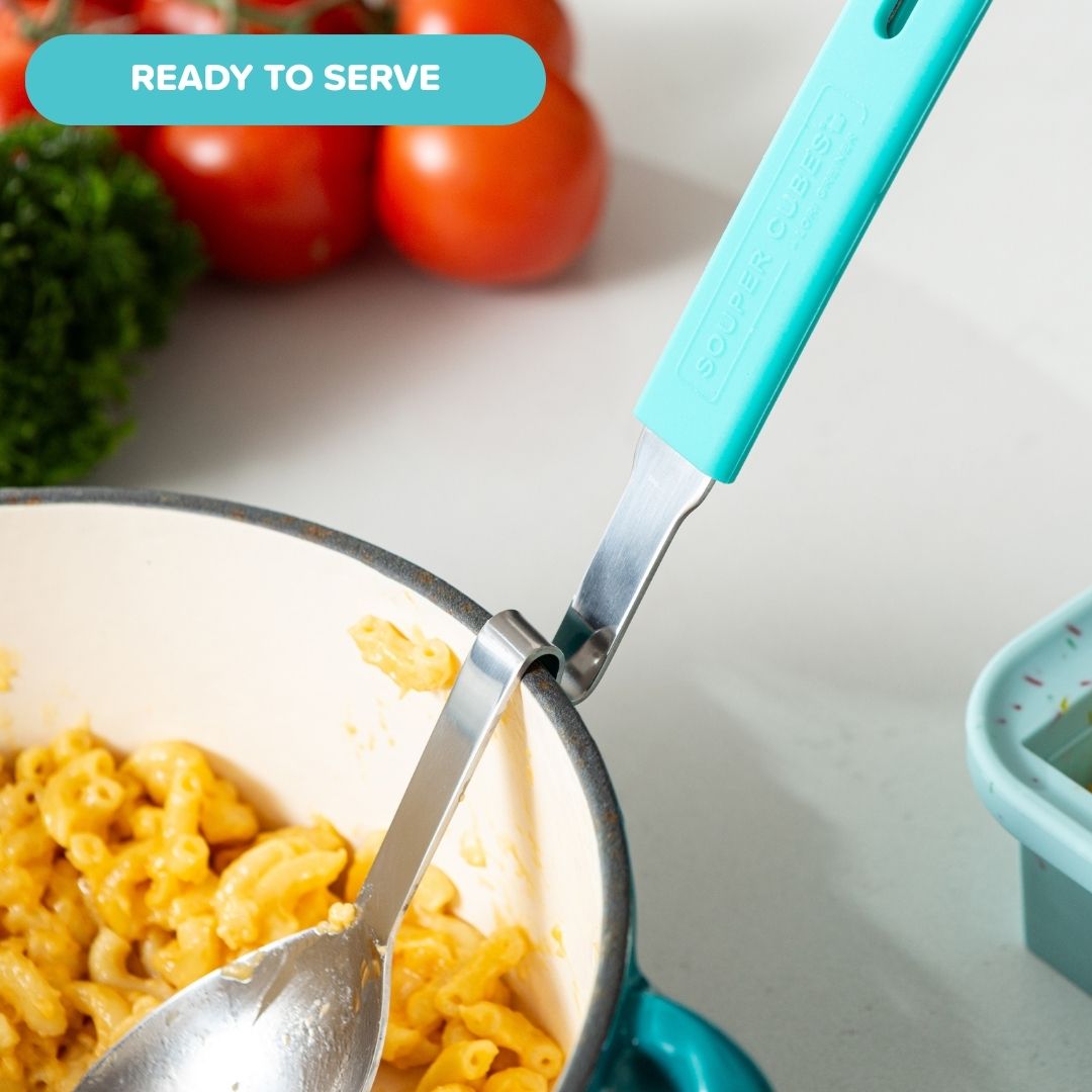Serving spoon resting on a pot full of  mac and cheese