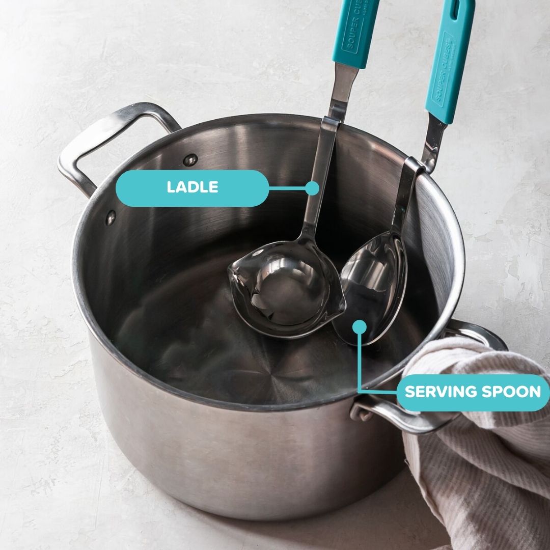 Stainless steel pot with ladle and serving spoon on a light gray background