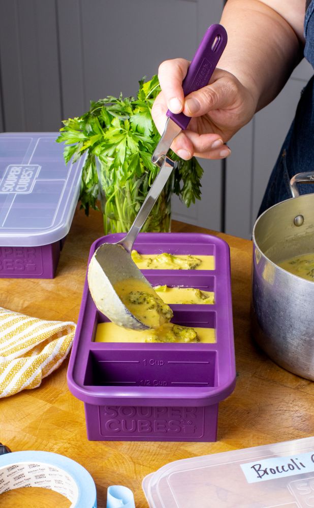 Filling a 1-cup Souper Cubes tray with broccoli cheddar soup.
